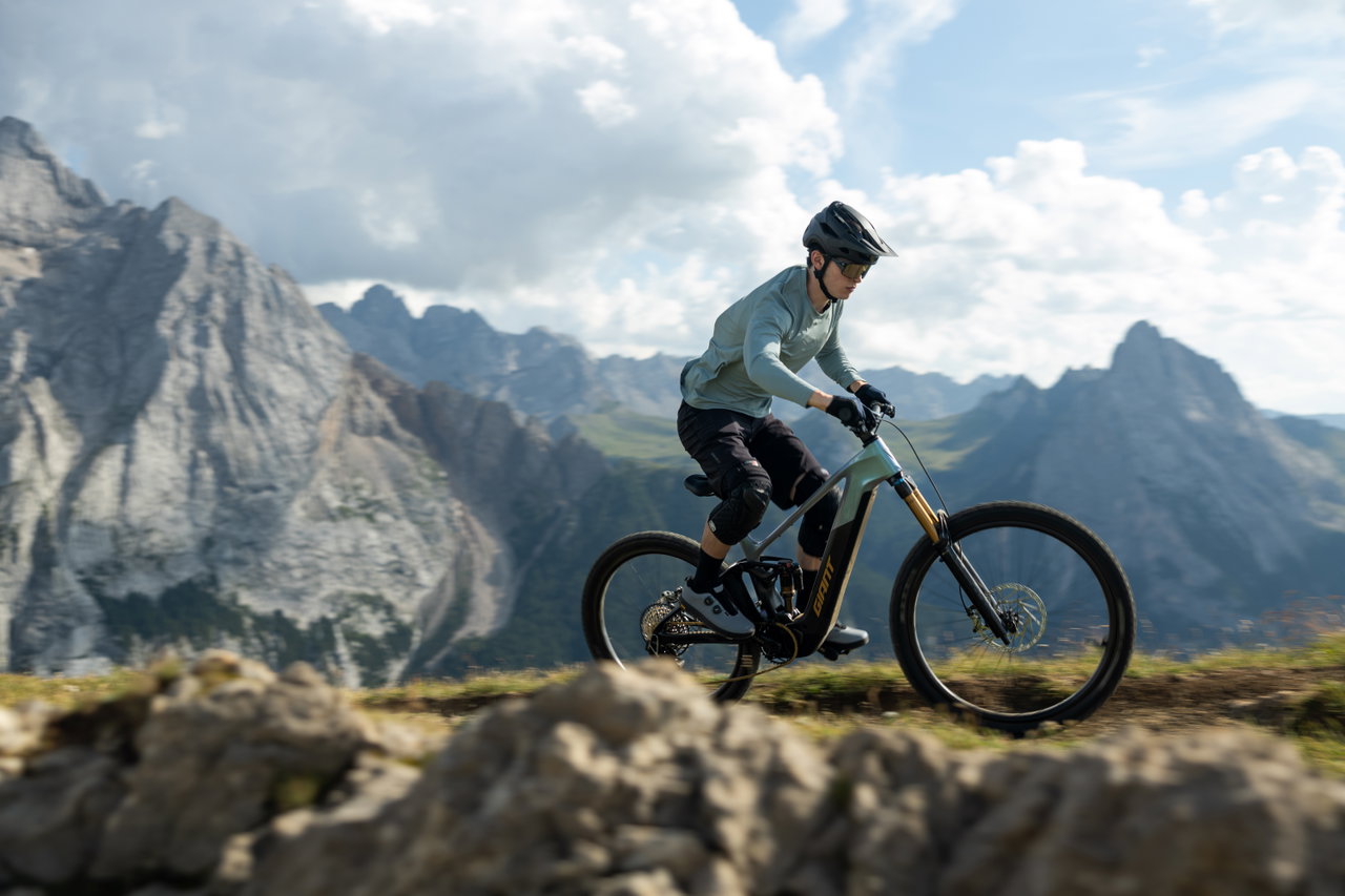Fahrer mit Giant Trance Advanced E+ auf einem alpinen Trail vor Bergkulisse